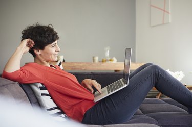 Smiling woman using laptop on couch at home