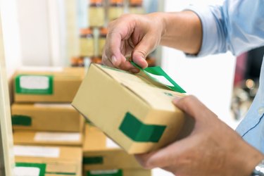 Cropped Hands Of Man Sticking Labels On Cardboard Boxes At Workshop