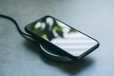 High Angle View Of Smart Phone Getting Charged On Table