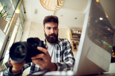 Young photographer beard man editing pictures at his home.