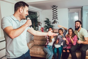 Group of friends playing karaoke at home