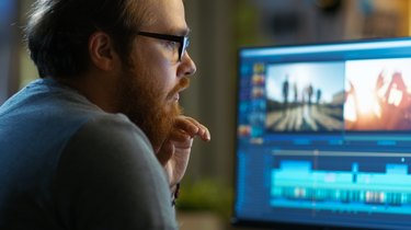 Male Video Editor Works with Footage and Sound on His Personal Computer. He Works in a Cool Office Loft.