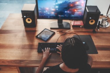 Young woman playing video games on computer at home