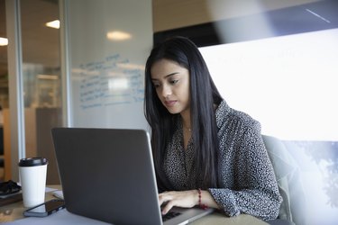 Focused businesswoman using laptop in conference room