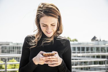 Smiling woman text messaging on roof terrace