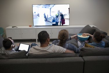 Family watching movie, eating popcorn on sofa