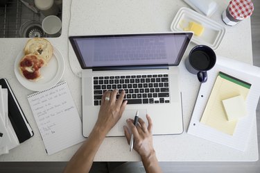 Overhead view woman working at laptop at breakfast kitchen counter