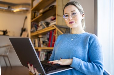 Female higher education student sitting on university stairway using laptop, portrait