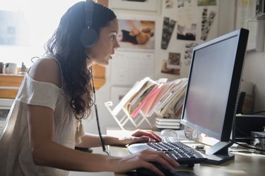 Hispanic woman listening to computer with headphones