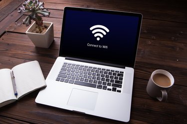 View of wi-fi connection on the laptop / computer screen with office equipment on wooden desk background