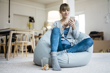 Smiling woman sitting in beanbag using cell phone