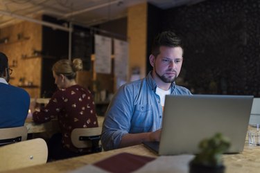 Businessman working late using laptop in cafe