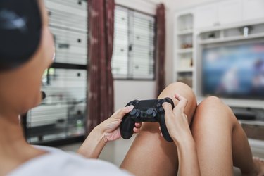 Asian woman play video game console at home