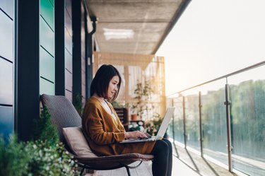 Young woman working on laptop in balcony