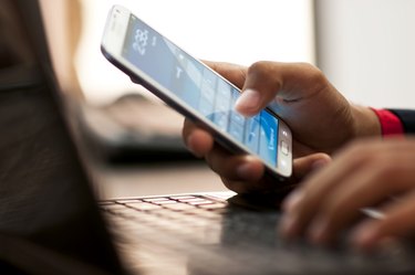 Businessman hand using laptop and mobile phone in office