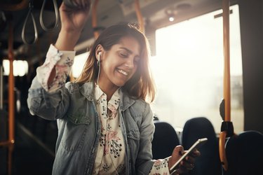 Smiling young woman riding on a bus listening to music