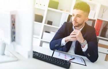 A young man sitting in the office at a computer Desk and working with documents.