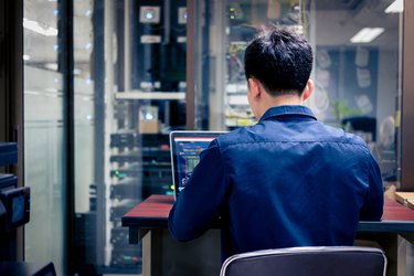 Technicians using laptop while analyzing server in server room