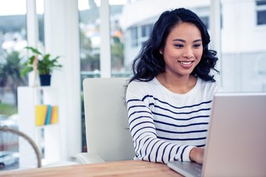Smiling Asian woman using laptop