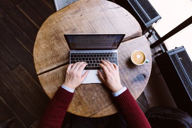 Directly above view of a man working on laptop in coffee shop, personal perspective view