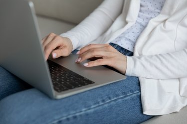 Woman puts notebook on laps do remote job distantly closeup