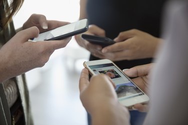 Close up teenage girl friends using cell phones