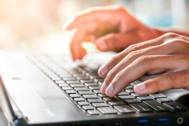 Close-up portrait of hands typing on laptop. Female businesswoman working on-line via laptop computer. Woman working at home office concept.