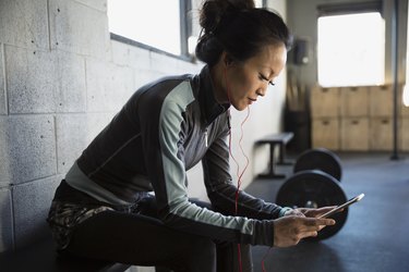 Woman with headphones using cell phone at gym