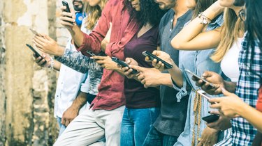 Group of multicultural friends using smartphone outdoors - People hands addicted by mobile smart phone - Technology concept with connected men and women - Shallow depth of field on vintage filter tone