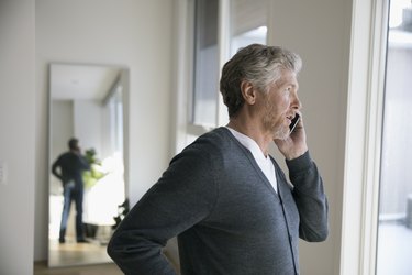 Senior man talking on cell phone, looking out window