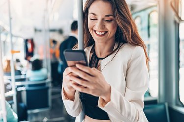 Smiling young woman with cell phone in the bus