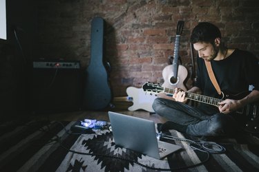 Young Musician Playing Guitar Sitting in front Notebook