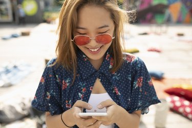 Teenage girl with sunglasses using smart phone