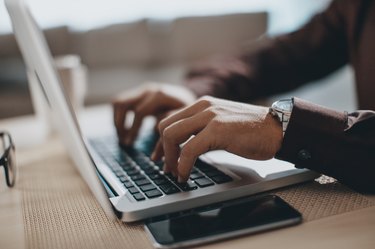 Hands typing on laptop computer