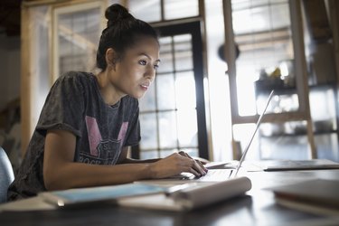 Focused young woman working at laptop in office