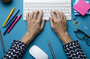 Top view of woman using computer keyboard on desk