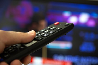 Man watching TV set and using remote control.