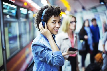 Smiling woman listening to headphones in subway