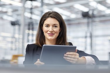 Female manager holding digital tablet in car plant