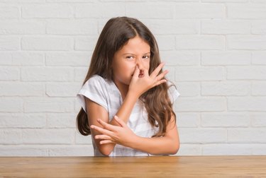 Young girl holding nose