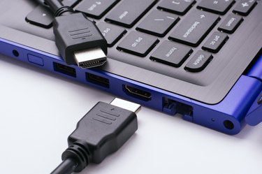 Two ends of the HDMI cable near the HDMI port of the modern blue laptop on a white background