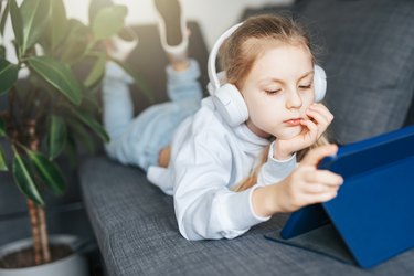 Little girl with headphones and tablet  at home