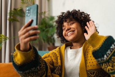 African american girl holding smartphone having video chat. Female blogger chatting with best friends in social network. Young woman having virtual meeting online chat video call at home.