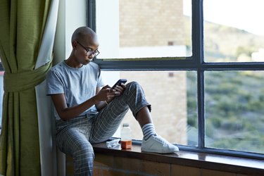 Bald female student text messaging through phone