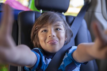 POV silly boy making a face, riding in back seat of mini van