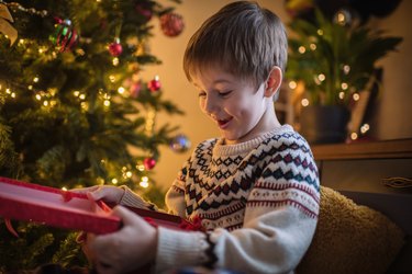 Cute little boy opens Christmas gifts