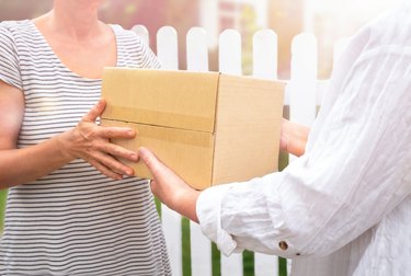 Courier handing the parcel to senior in front of the house