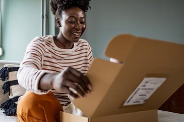 Smiling African American woman opening her online delivery box
