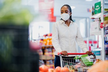 Woman shopping in supermarket wearing coronavirus face mask.