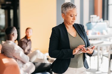 Leader and business woman on a digital tablet in a modern corporate office. Mature confident entrepreneur feeling ambitious and motivated for success while planning schedule online with app at work